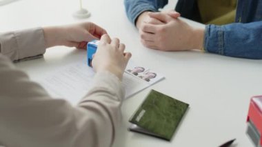 Kadın konsolosluk görevlisinin Shengen vizesi başvuru formuna onaylanmış damgayı basıp, sonra da AB büyükelçiliğindeki röportajdan sonra genç ve neşeli adama belge ve pasaport verirken görüntüsünü kaldır.