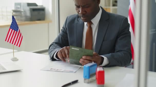 米国大使館での勤務中にパスポートと申請書を確認するアフリカ系アメリカ人ビザ担当官 — ストック動画