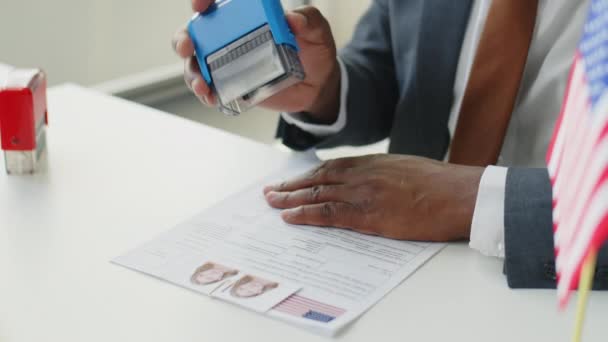 米国大使館で勤務中にアフリカ系アメリカ人男性ビザ担当官が申請書に承認されたスタンプを押す — ストック動画