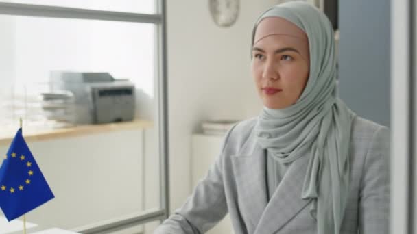 Nuori Musliminainen Hijabissa Tarkistamassa Naispuolisen Viisuminhakijan Asiakirjoja Kuuntelemassa Häntä Työskennellessään — kuvapankkivideo