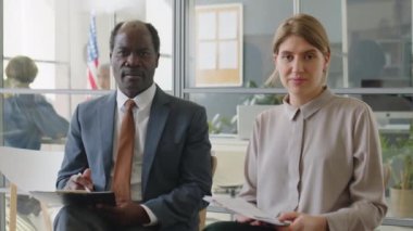 Beyaz kadın ve Afro-Amerikan iş adamlarının portresi ABD elçiliğinde kuyrukta oturuyor ve vizeyi beklerken kameraya poz veriyor.