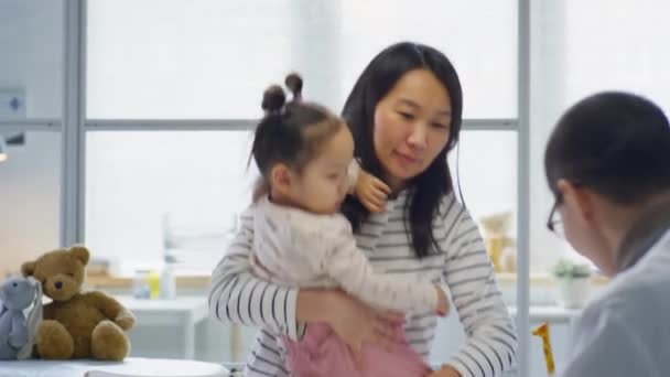 아시아인 어머니가 아기를 진료실에서 소아과 의사와 이야기하는 — 비디오