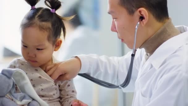 아시아 의사가 실에서 검진을 청진기를 귀여운 아기를 — 비디오
