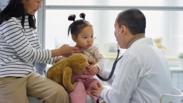 Ázsiai Gyermekorvos Sztetoszkóppal Miközben Egészségügyi Szűrést Kislánynak Aki Anya Mellett — Stock videók
