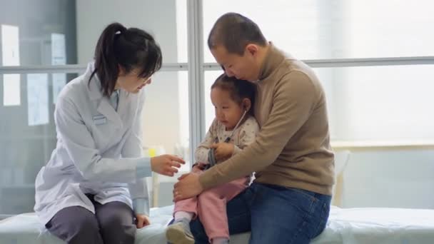 Roztomilá Malá Asijská Dívka Sedí Otcem Ženou Pediatr Gauči Hraje — Stock video