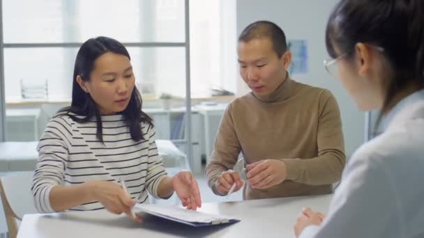 亚洲家庭夫妇在与怀孕诊所女医生协商期间签署合同 — 图库视频影像