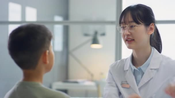 Азиатская Женщина Врач Осматривает Горло Шею Мальчика Подростка Время Медицинского — стоковое видео
