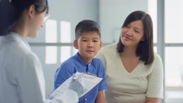Ázsiai Tinédzser Fiú Anyja Beszél Női Orvos Ahogy Jegyzetel Vágólapon — Stock videók