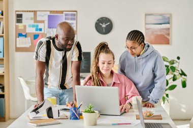 Görevde çalışan çok ırklı bir grup meslektaşı, birlikte dizüstü bilgisayardaki yeni yazılımın geliştirilmesini tartışıyor.