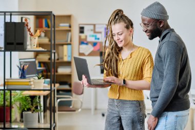 Çok ırklı meslektaşlar görevdeyken dizüstü bilgisayarda projeyi tartışıyorlar