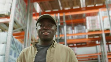 Depoda durup gülümseyerek kameraya poz veren neşeli Afrikalı Amerikalı erkek işçinin portresi.