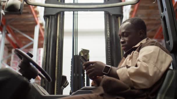 Powiększ Ujęcie Afroamerykańskiego Pracownika Magazynu Siedzącego Wózku Widłowym Sms Ującego — Wideo stockowe