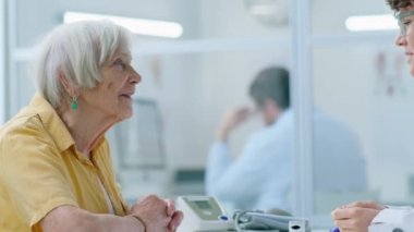 Eldelry kadınının klinikteki tıbbi danışmanlık sırasında kadın doktorla konuşurken görüntüsü.