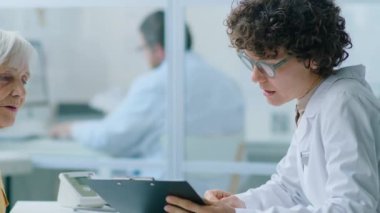 Kadın doktora tıbbi geçmişini veren ve klinikteki sağlık danışmanlığı sırasında onu dinleyen yaşlı bir kadın.