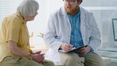 Erkek doktor ve Eldelry kadın hastasının klinikteki kanepede otururken tartıştıklarını çek.