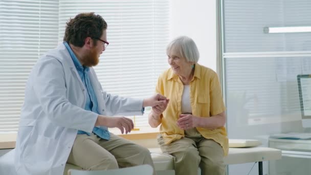 Προσεκτική Αρσενικό Γιατρό Κρατώντας Χέρι Της Γυναίκας Eldelry Και Μιλώντας — Αρχείο Βίντεο