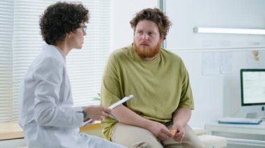 Klinikte danışmanlık yaparken kilolu bir adama nasıl kilo verileceğini öneren kadın doktor.