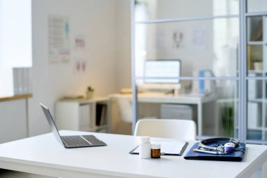 Masada dizüstü bilgisayarı ve ilacı olan modern bir doktor.