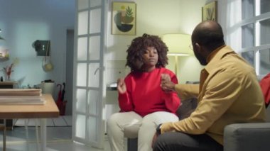 Sinirli Afro-Amerikan evli çift oturma odasında kanepede oturuyor ve duygusal kavga ediyorlar.