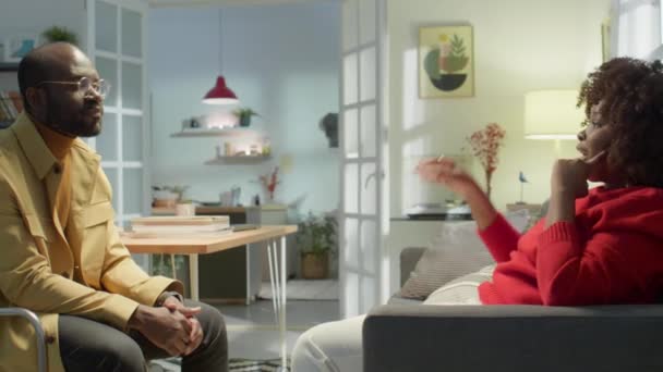 自宅で紛争を解決しながら アフリカ系アメリカ人の妻はリビングルームでソファに座って 夫に彼女の気持ちを説明します — ストック動画