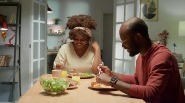 Neşeli bir Afrikalı Amerikalı kadının evde yemek yerken kocasıyla sohbet edişine zum yap.