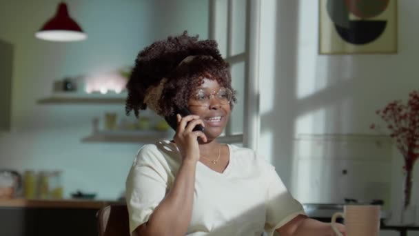 Afroamerykanka Siedzi Przy Stole Kubkiem Herbaty Rozmawia Przez Telefon Wieczorem — Wideo stockowe