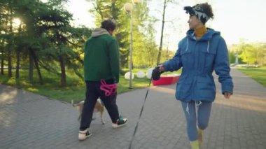 Neşeli genç kadın güneşli bir günde parkta güzel bir Corgi köpeğiyle yürümekten zevk alıyor.