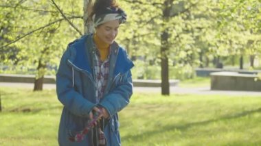 Güzel güneşli bir günde güzel bir Corgi köpeğiyle parkta yürürken gülümseyen ve ip oyuncağı tutan genç bir kadın.