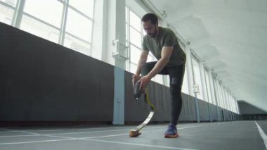 Sporcu protez koşu bıçağı takıyor ve kapalı stadyumda koşmaya başlıyor.