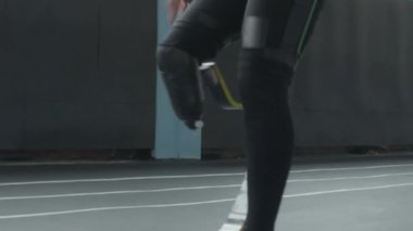 Antrenman sırasında protez bacaklı erkek sporcunun yüksek dizleriyle stadyum pistinde koşarkenki yavaş çekimini kapat.