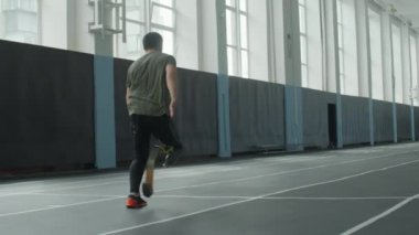 Stadyumda koşan protez bacaklı profesyonel sporcunun yavaş çekim görüntüsü.