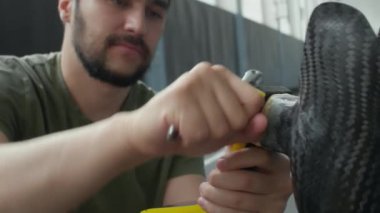 Profesyonel erkek sporcu stadyumda koşuya hazırlanırken ingiliz anahtarıyla protezi tamir ediyor.