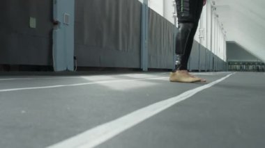 Stadyumda çeviklik egzersizi yapan protez bacaklı profesyonel erkek sporcunun bacakları.