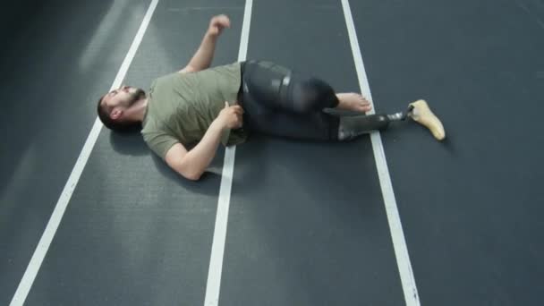 男子假腿运动员在室内体育场做仰卧起坐和伸展运动 — 图库视频影像