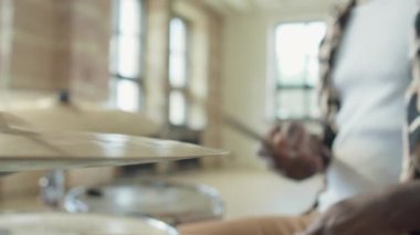 Afrikalı Amerikalı bir adam müzik stüdyosunda davul çalıyor.