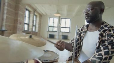 Müzik stüdyosunda davul çalan siyah bir adam.