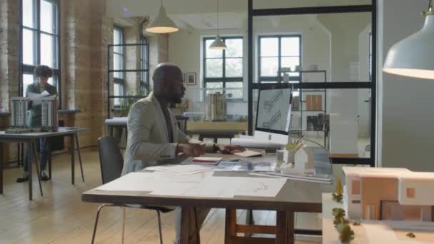 Zoom Toma Arquitecto Afroamericano Mecanografiando Computadora Tomando Notas Papel Escritorio — Vídeos de Stock