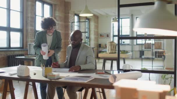 非洲裔美国男性建筑师和他的白人女同事在一起工作的同时讨论着纸的计划 — 图库视频影像