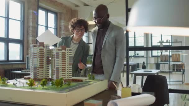 Kaukasische Architektin Diskutiert Papiermodelle Von Wohngebäuden Mit Afroamerikanischen Männlichen Kollegen — Stockvideo