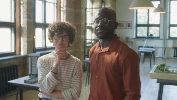 アフリカ系アメリカ人男性と白人女性の肖像建築事務所でカメラのために一緒にポーズ — ストック動画