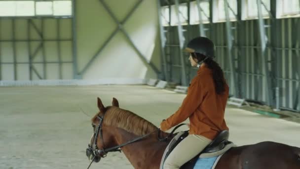 Młoda Kobieta Kasku Ujeżdżająca Konia Hali Podczas Lekcji Instruktorem Szkole — Wideo stockowe