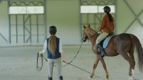 Mujer Cabalgando Caballo Castaño Liderado Por Instructora Durante Lección Escuela — Vídeo de stock