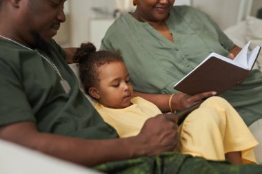 Babası üniformalı, ailesiyle evde vakit geçiriyor.