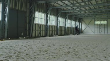 İç mekanda kasklı ata binen profesyonel bayan jokeyin yavaş çekim çekimi.