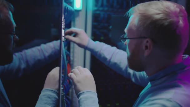 Manlig Tekniker Inspektera Serverkablar Medan Arbetar Mörka Datacenter Med Neonljus — Stockvideo