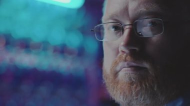 Veri merkezinde sistem yöneticisi olarak çalışırken karanlık sunucu odasında kameraya poz veren beyaz sakallı adamın portresi