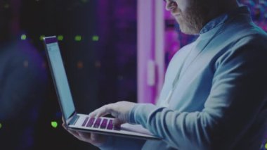 Veri merkezinde çalışırken dizüstü bilgisayarda yazı yazan sunucu yöneticisinin kırpılmış görüntüsü