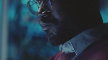 Koyu renk veri merkezinde, dizüstü bilgisayardaki Afrikalı Amerikalı programcının yakın çekim görüntüsü.