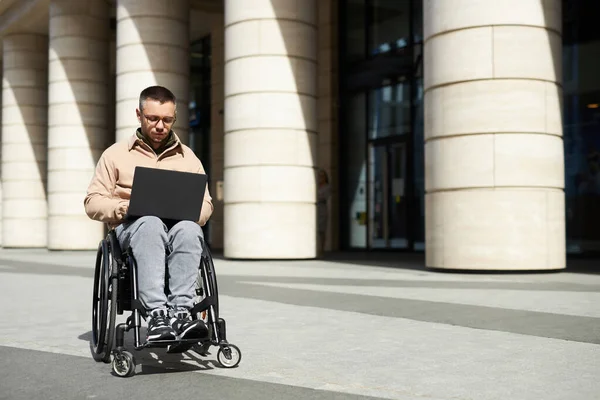 Молодой Человек Ограниченными Возможностями Сидит Инвалидной Коляске Печатает Ноутбуке Снаружи — стоковое фото