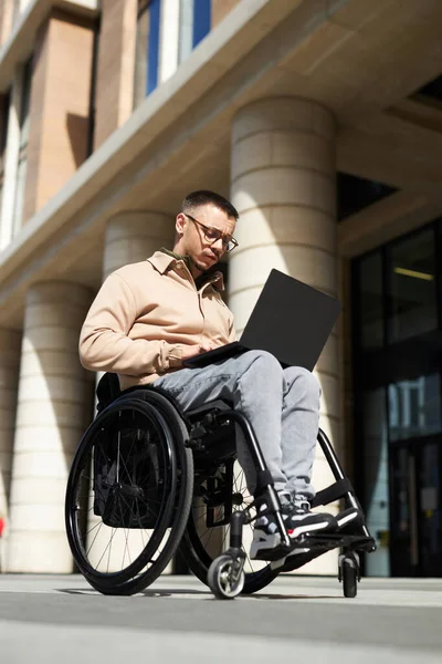 Вертикальное Изображение Молодого Человека Сидящего Инвалидной Коляске Использующего Ноутбук Городе — стоковое фото